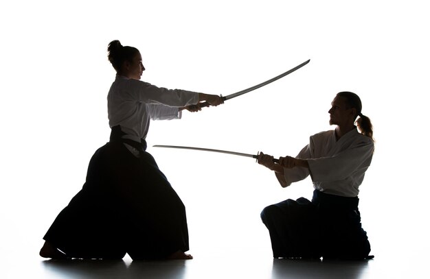 Man and woman fighting and training aikido on white studio wall