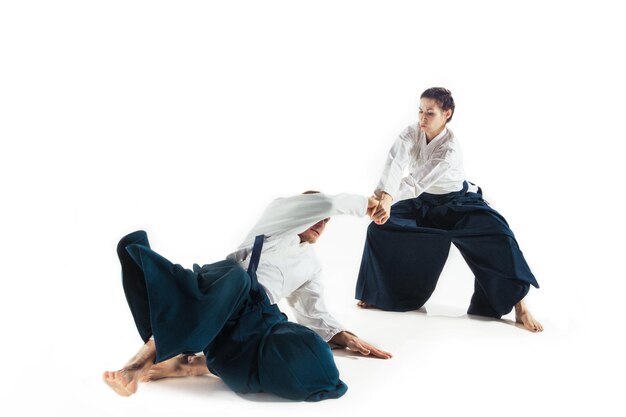 Man and woman fighting and training aikido on white studio wall