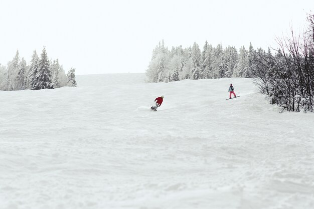 Man and woman go down the hill on the snowboards 