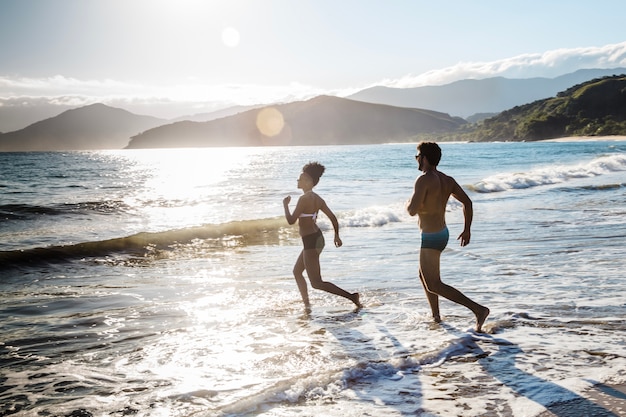 Free photo man and woman going into the water at the beach