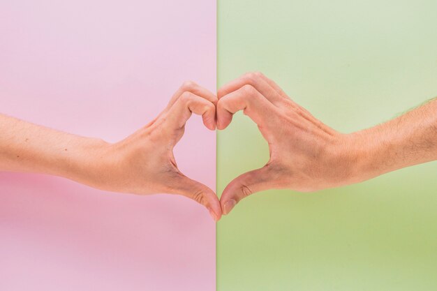 Man and woman hands showing symbol of heart 