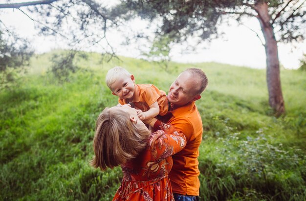 Man and woman have fun with their son in the forest 