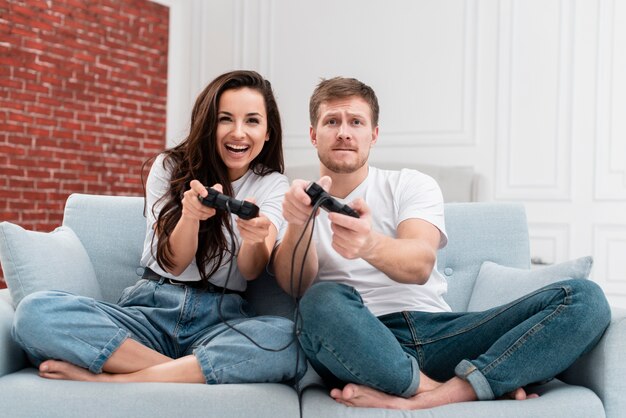 Man and woman having fun while playing with controllers