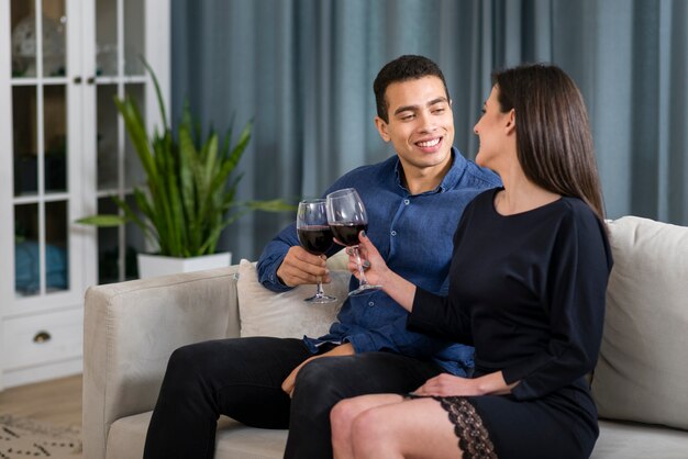 Man and woman having a glass of wine while sitting on the couch