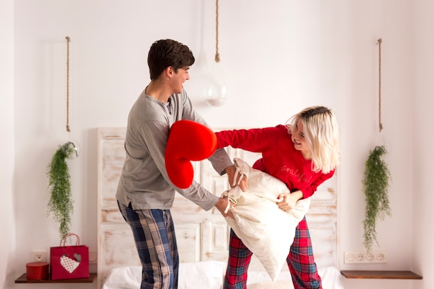 Uomo e donna che hanno una lotta di cuscini in camera da letto