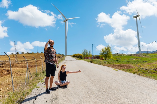 Man and woman hitchhiking on road