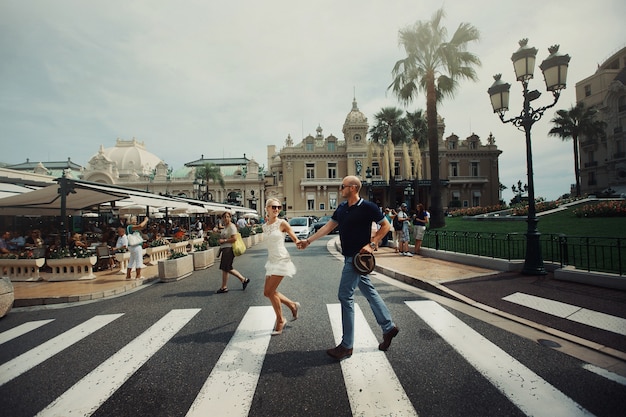 Man and woman hold each other hands crossing street in Monte Carlo