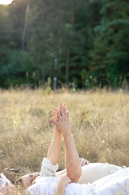 Foto gratuita un uomo e una donna si tengono per mano mentre giacciono nell'erba in un campo