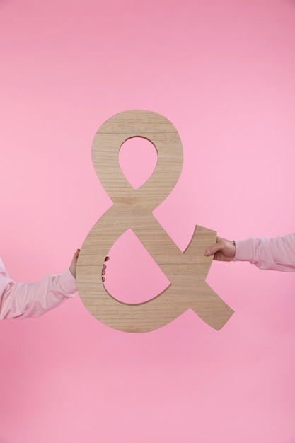 Free photo man and woman holding big symbol of ampersand