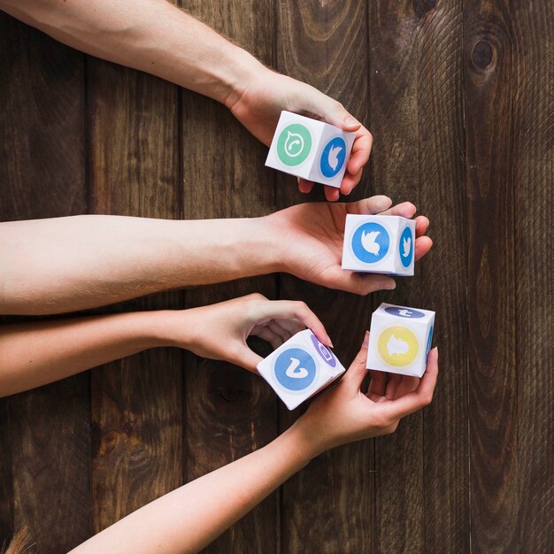 Man and woman holding blocks of social media icons on wooden table