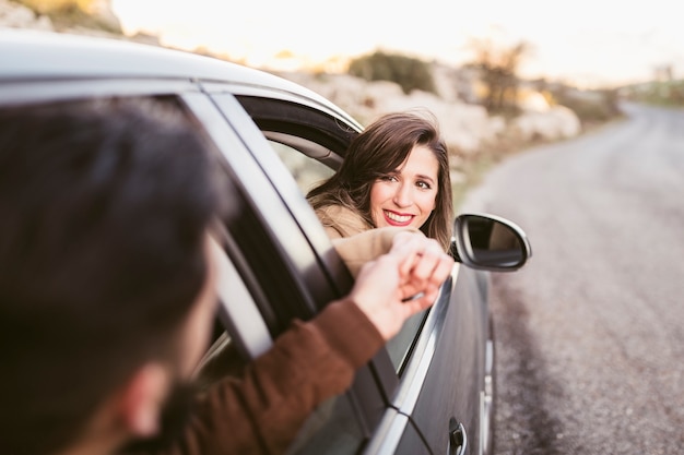 Free photo man and woman holding hands outside of car