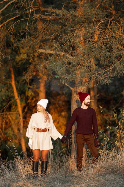 Man and woman holding hands next to trees