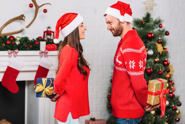 Man and woman holding presents from backs 