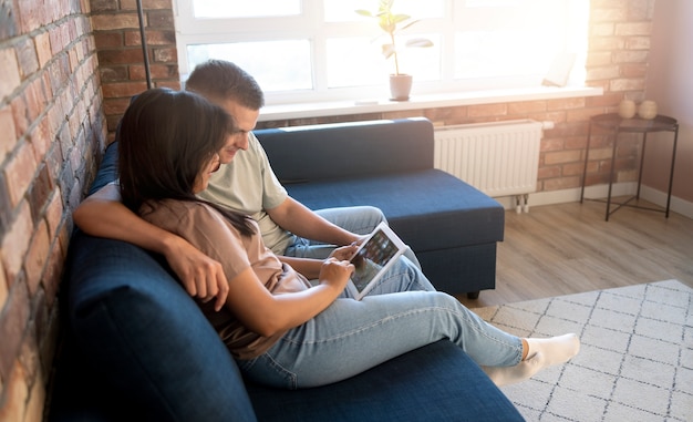 Uomo e donna a casa che utilizzano tablet per lo shopping online