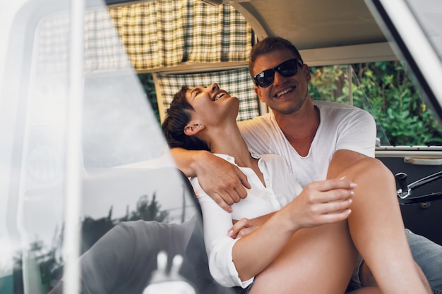 Man and woman hug and smile sitting in an old bus