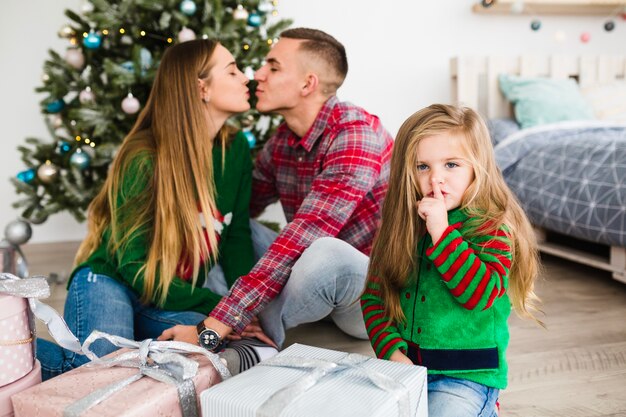 Man and woman kissing in front of christmas tree
