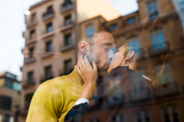 Free photo man and woman kissing in restaurant near window