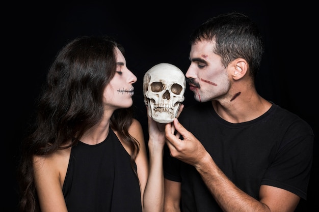 Free photo man and woman kissing skull