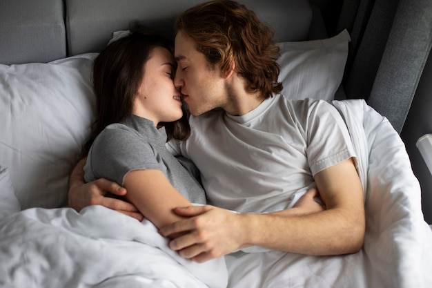 Man and woman kissing while in bed