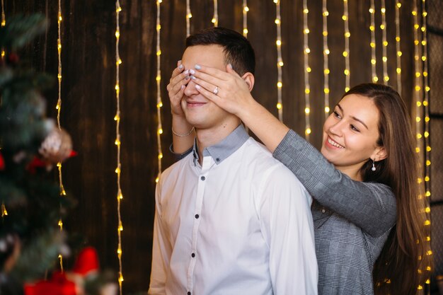 男と女は、赤いクリスマスツリーの前に美しいポーズをとります