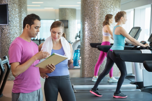 Man and woman looking at a paper while two girls walk on the machines