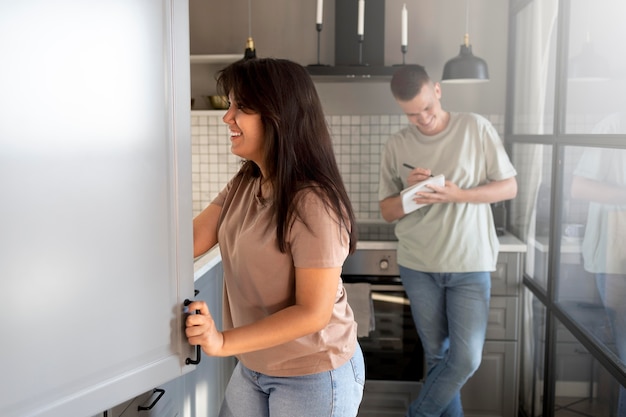 Man and woman making shopping list at home in the kitchen together