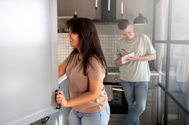 Мужчина и женщина вместе составляют список покупок дома на кухне