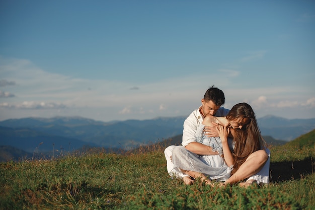Man and woman in the mountains. Young couple in love at sunset. Woman in a blue dress.