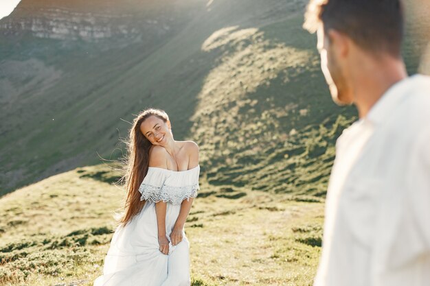 山の中の男と女。日没で恋をしている若いカップル。青いドレスを着た女性。