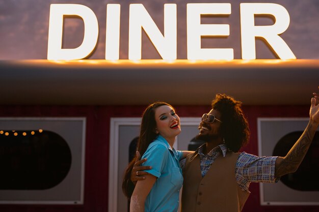 Мужчина и женщина позируют в стиле ретро возле закусочной