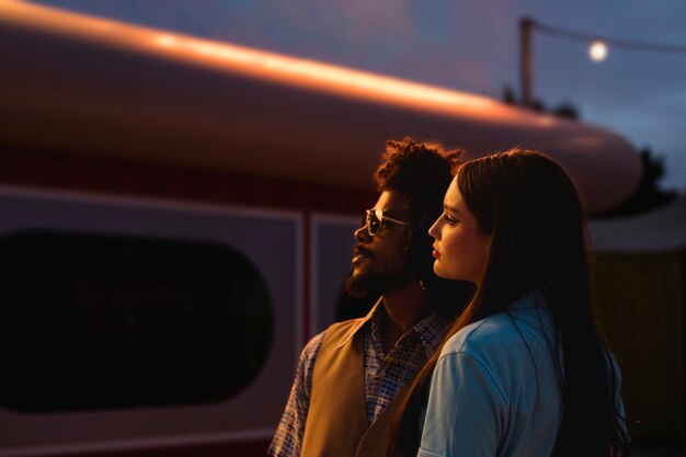 Man and woman posing together in retro style at night with lights