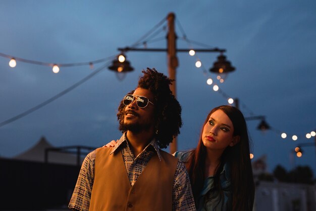 Man and woman posing together in retro style at night with lights