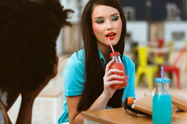 Man and woman posing together in retro style with camera and beverage