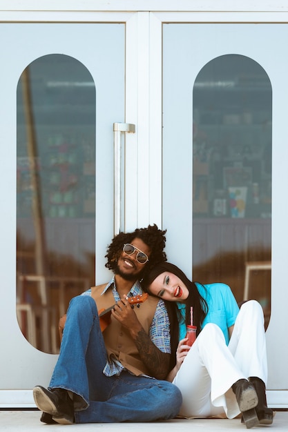 Man and woman posing together in retro style with ukulele and beverage