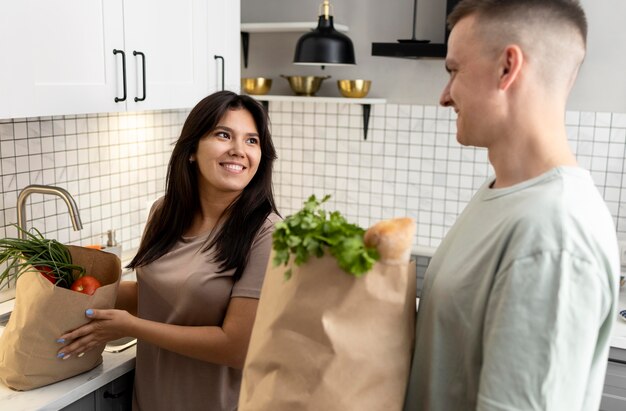Мужчина и женщина получают бумажные пакеты для продуктов после покупок в Интернете