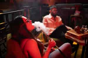 Free photo man and woman relaxing by vaping from a hookah in a bar