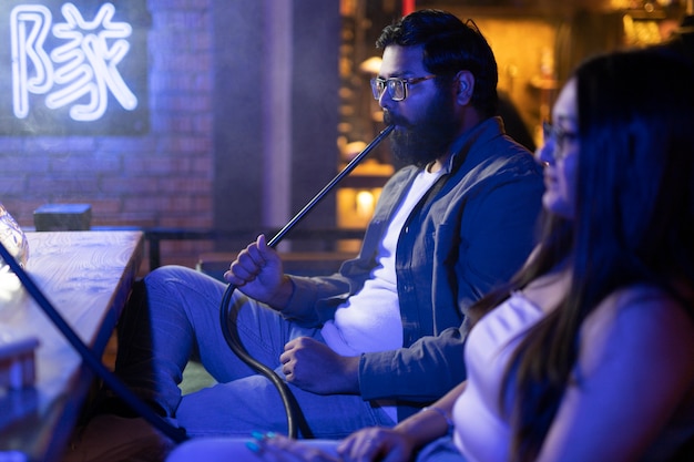 Man and woman relaxing by vaping from a hookah in a bar