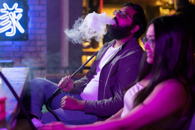 Man and woman relaxing by vaping from a hookah in a bar