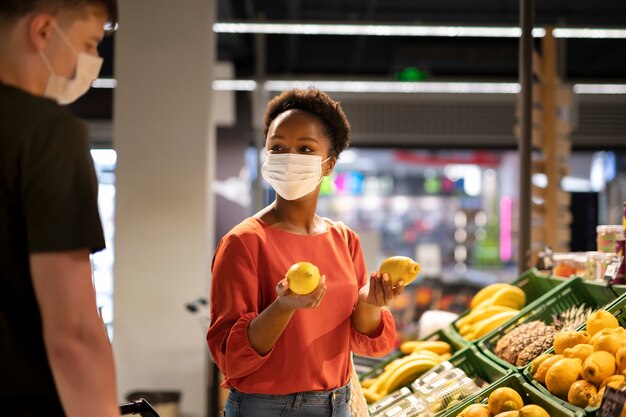 의료용 마스크를 쓰고 식료품점에서 쇼핑하는 남녀
