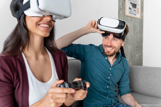 Мужчина и женщина сидят на диване дома и используют гарнитуру виртуальной реальности