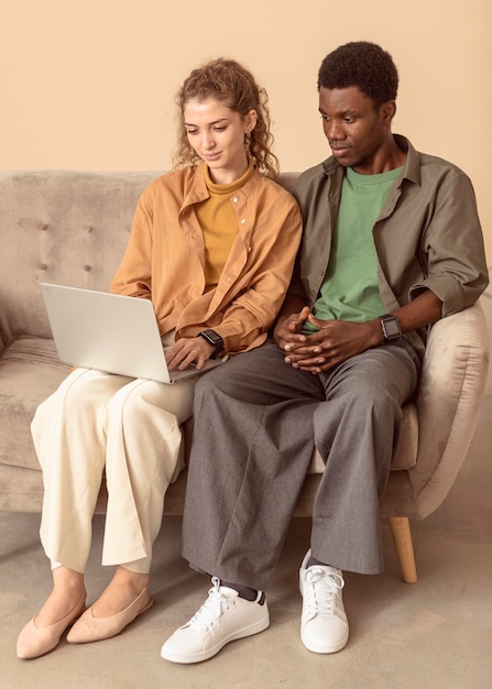 Man and woman sitting on the couch and using laptop