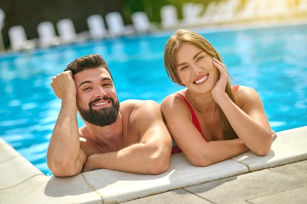 수영장에서 카메라를 보며 웃고 있는 남자와 여자