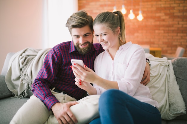 Мужчина и женщина улыбается и использует смартфон