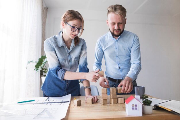 Мужчина и женщина укладывают деревянный блок на рабочий стол в офисе