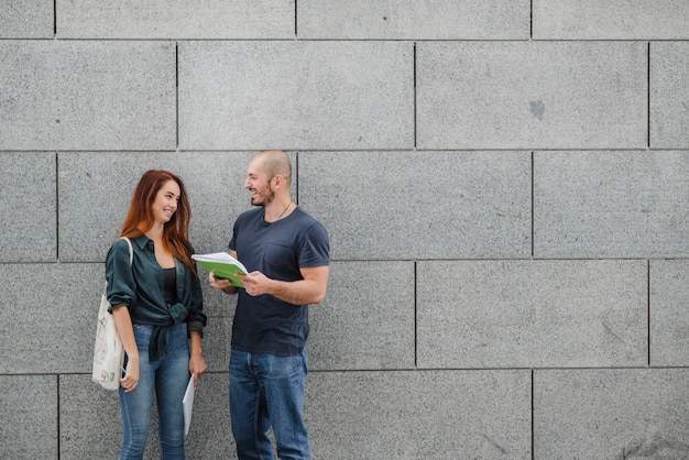 Man and woman standing against gray wall