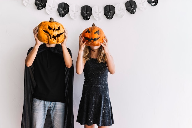 Free photo man and woman standing with pumpkin faces