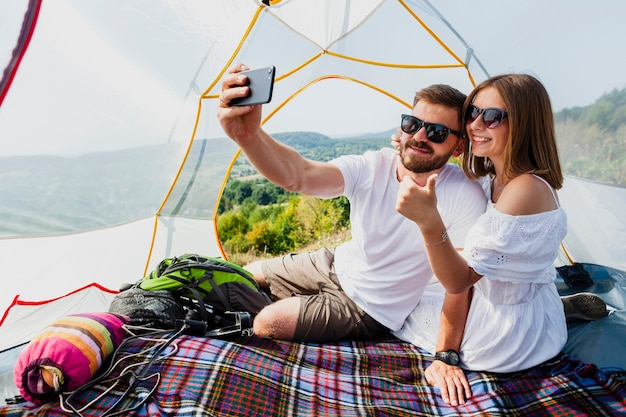 Мужчина и женщина фотографируют себя в палатке