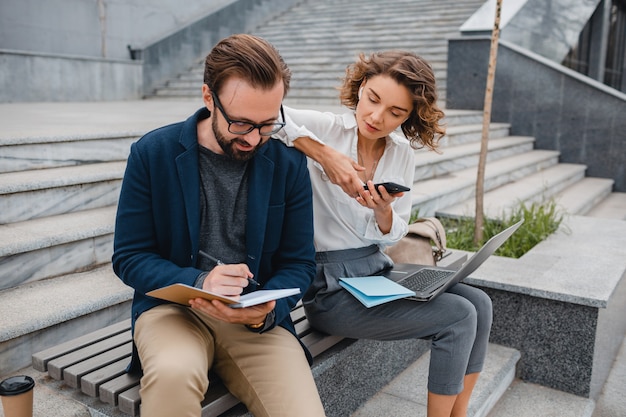 Man and woman talking sitting on stairs in urban city center