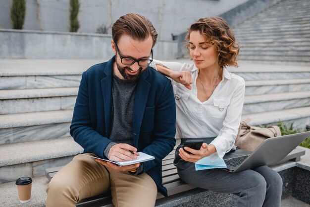 Man and woman talking sitting on stairs in urban city center