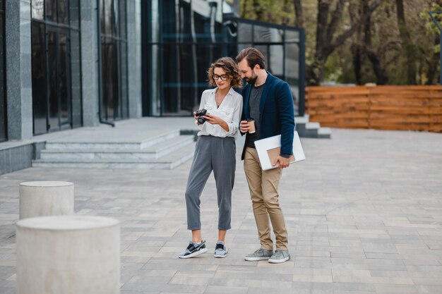 Man and woman talking in urban city center, discussing, taking pictures for project on digital photo camera